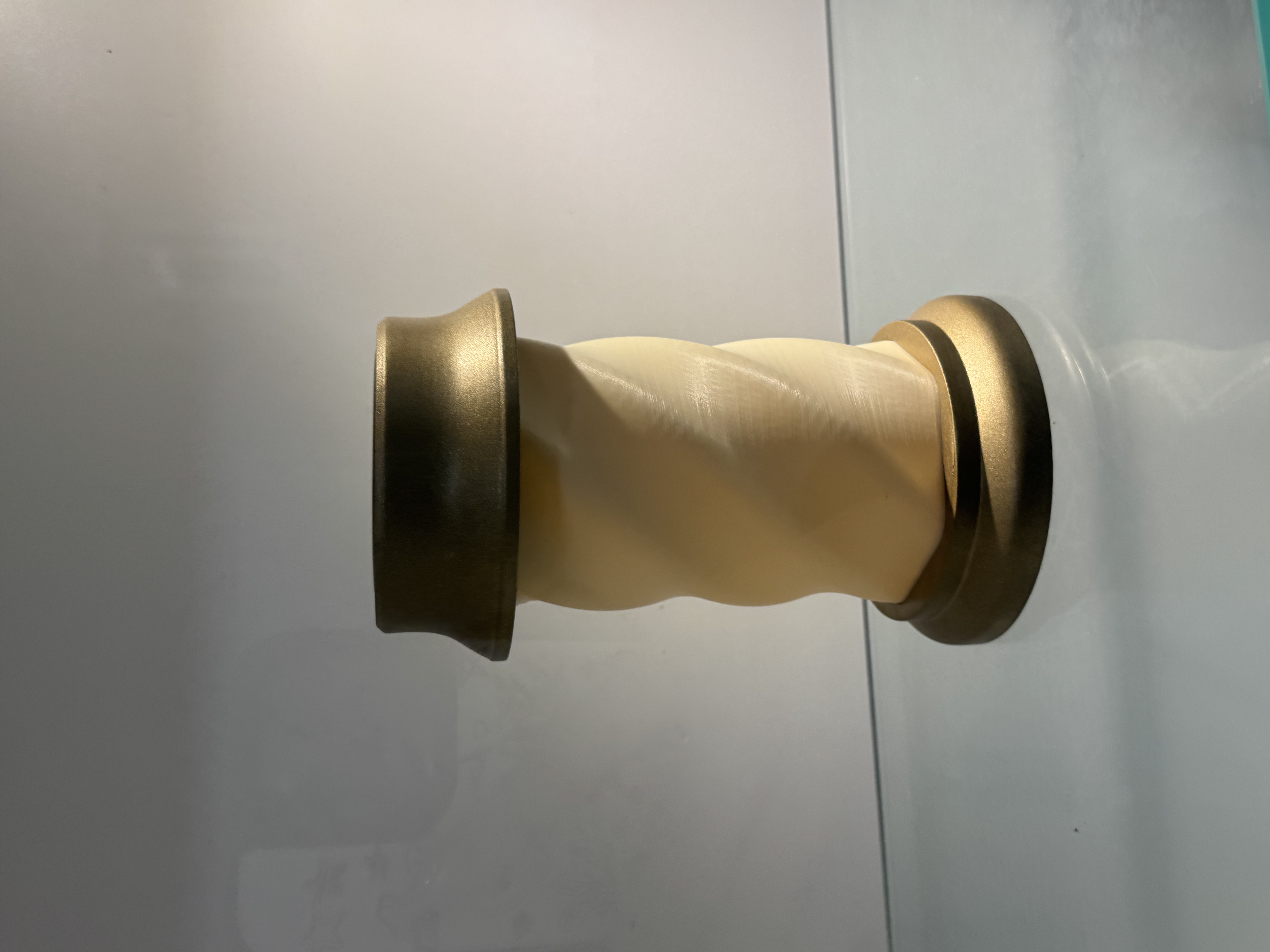 The beige middle part has spiral patterns, looks like 3D-printed plastic. The golden parts on the top and bottom have a metallic shine, but they look more like spray-painted or coated plastic rather than real metal. So overall, it is likely 3D-printed plastic with metallic spray paint.<a href='https://www.youtube.com/embed/tgbNymZ7vqY' target='_blank'><p>Project Video Link</p></a>